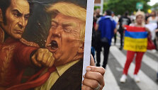 Protestuotojai laiko plakatą, kaip Simonas Bolivaras tariamai smogia Donaldui Trumpui