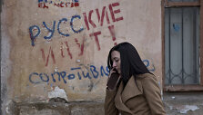 FILE - In this Friday, March 7, 2014 file photo, a woman passes by a graffiti that reads "The Russians are coming - Resistance" in Simferopol, Ukraine. For the ethnic Ukrainians and Tatars who are the minority in the strategic peninsula, it is fear that dominates days before Crimea votes in a refere