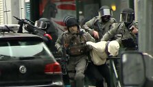 Belgijos policininkai veda penktadienį sulaikytą asmenį.