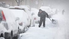 Čikagoje vyras prie savo automobilio kasa sniegą.