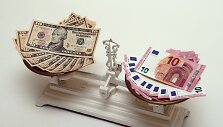 10 eurų ir 10 JAV dolerių banknotai ant svarstyklių 