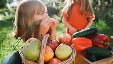 little-girls-lie-on-grass-in-garden-next-to-wicker-2023-11-27-05-34-52-utc