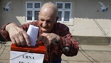 Senukas meta rinkimų lapelį į mobilią balsavimo dėžutę.
