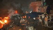 Vietos gyventojai mėgina užgesinti po aviakatastrofos įsiplieskusį gaisrą.