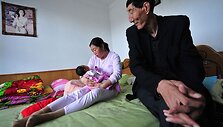 Auk&scaron;čiausias vyras sėdi &scaron;alia savo žmonos Xia Shuyun ir jų naujagimio Tianyou