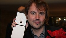 Oskaras Kor&scaron;unovas matuojasi gautą Boriso Dauguviečio premiją-auskarą