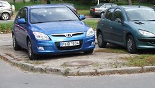 Mėlynasis prokurorės automobilis ant i&scaron;važinėto žolės ploto.