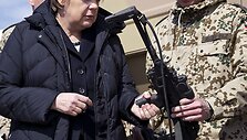 Vokietijos kanclerė Angela Merkel laiko kulkosvaidį.