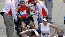 Medikai į vežimėlį sodina sunegalavusį Bostono maratono dalyvį.