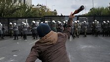 Protestuotojas meta butelį į policininkus.