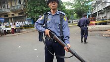 Mianmaro policininkas budi prie gaisro nuniokotos mokyklos.