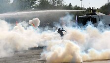 Tarp a&scaron;arinių dujų bėgantis protestuotojas