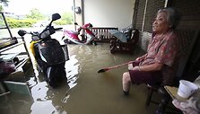 Moteris sėdi prie savo apsemto namo