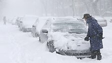 Vyras valo sniegą nuo automobilio