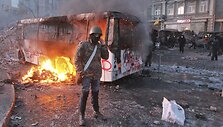 Protestuotojas prie sudegusio autobuso Kijeve
