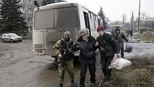 Ukrainos karys padeda vyrui pasiekti autobusą, kuriuo evakuojami gyventojai i&scaron; Debalcevės miesto.