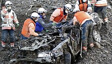 Gelbėtojai prie sulamdyto automobilio.