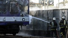 Gaisrininkai gesina padegtą keleivinį traukinį.