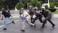 Policininkai vaiko protestuotojus Atėnuose.