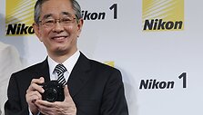 &bdquo;Nikon&ldquo; prezidentas Makoto Kimura laiko &bdquo;Nikon 1 V1&ldquo; veidrodinį fotoaparatą.