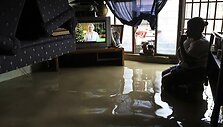 Moteris apsemtame kambaryje žiūri televizorių.