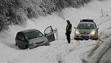 Policininkas stovi &scaron;alia nuo kelio nuslydusio automobilio