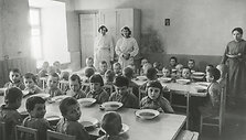 Prie&scaron;mokyklinio amžiaus karo atbėgėlių vaikučiai prie stalo pietų metu. Įdomu, kas tose mažose jų galvutėse, tur būti dar prisimenančiose, kad vos prie&scaron; keletą mėnesių jie pietaudavo savo tėvų namuose, o dabar tenka nuo &scaron;eimų atskirtiems, dažnai ir tėvę netekus, glaustis ir misti tarp nepažįstamų žm