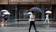 Praėjusieji su skėčiais vaik&scaron;to Fukuokos tajfuno lietuje. / Issei Kato / via REUTERS