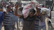 Palestiniečiai ne&scaron;asi maisto produktų mai&scaron;us i&scaron; pagalbos skirstymo centro / Abdel Kareem Hana / AP