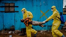 Balandžio 20 diena. Darbinikai ne&scaron;a berniuką, kuris kaip įtariama, užsikrėtęs ebola, į gydymo centrą Liberijoje