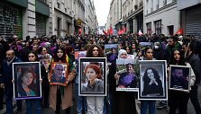 Demonstrantai ne&scaron;a Paryžiuje nužudytų kurdų portretus.