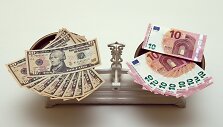 10 eurų ir 10 JAV dolerių banknotai ant svarstyklių 