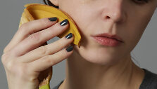 Moteris banano žieve trina sau veidą