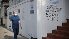 Vyras Londone greta sienos su užra&scaron;u skelbiančiu esą COVID-19 pandemija buvo pradėta 5G ry&scaron;io tinklui i&scaron;plėsti