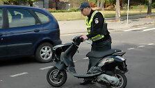 Policininkas apžiūri sudaužytą mopedą