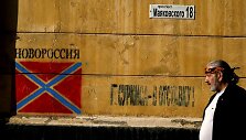 Vyras eina pro grafitį su apsi&scaron;aukeli&scaron;kos &bdquo;Novorosijos&ldquo; vėliava Donecke
