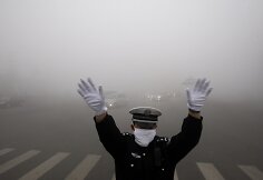 Policininkas per smogą bando reguliuoti eismą sankryžoje.