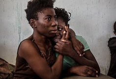 Dvi pabėgėlės iš Nigerijos verkia migrantų sulaikymo centre Libijoje