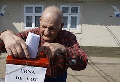 Senukas meta rinkimų lapelį į mobilią balsavimo dėžutę.