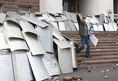 Policininkai nuo svaidomų plytų slepiasi po skydais.