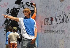 Žmonės pasirašinėja ant Michaelo Jacksono plakato.