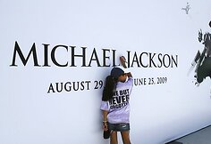 Mergaitė pirmoji pasirašo ant Michaelo Jacksono plakato.