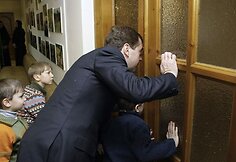 Dmitrijus Medvedevas su vaikais žiūri pro durų tarp.