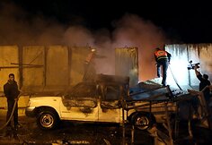 Palestiniečiai prie degančio automobilio, į kurį pataikė Izraelio raketa