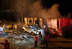 Palestiniečiai prie degančio automobilio, į kurį pataikė Izraelio raketa