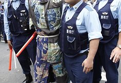 Policijos pareigūnai stumia protestuotoją.
