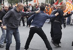 Civiliais rūbais vilkintis policininkas (kairėje) tramdo demonstrantą.