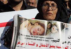 Moteris laiko batą ir palestiniečių aukų nuotrauką...