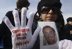 Rankoje protestuotoja laiko savo tėvo, kurį nužudė italų mafija, nuotrauką.