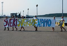 Grįžtantis burlaivis pasitiktas su plakatais.
